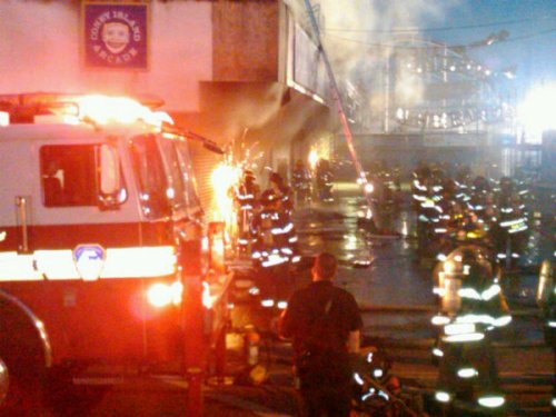 Firefighters sawing into Coney Island Arcade thru the shutters to access fire.  Photo © Adam Richman via twitpic